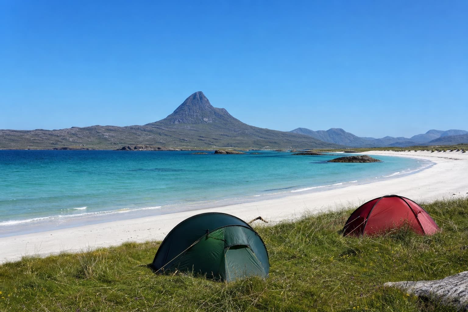 Tents pitched beside a white-sand beach and turquoise sea below a Highland mountain in Assynt on the NC500